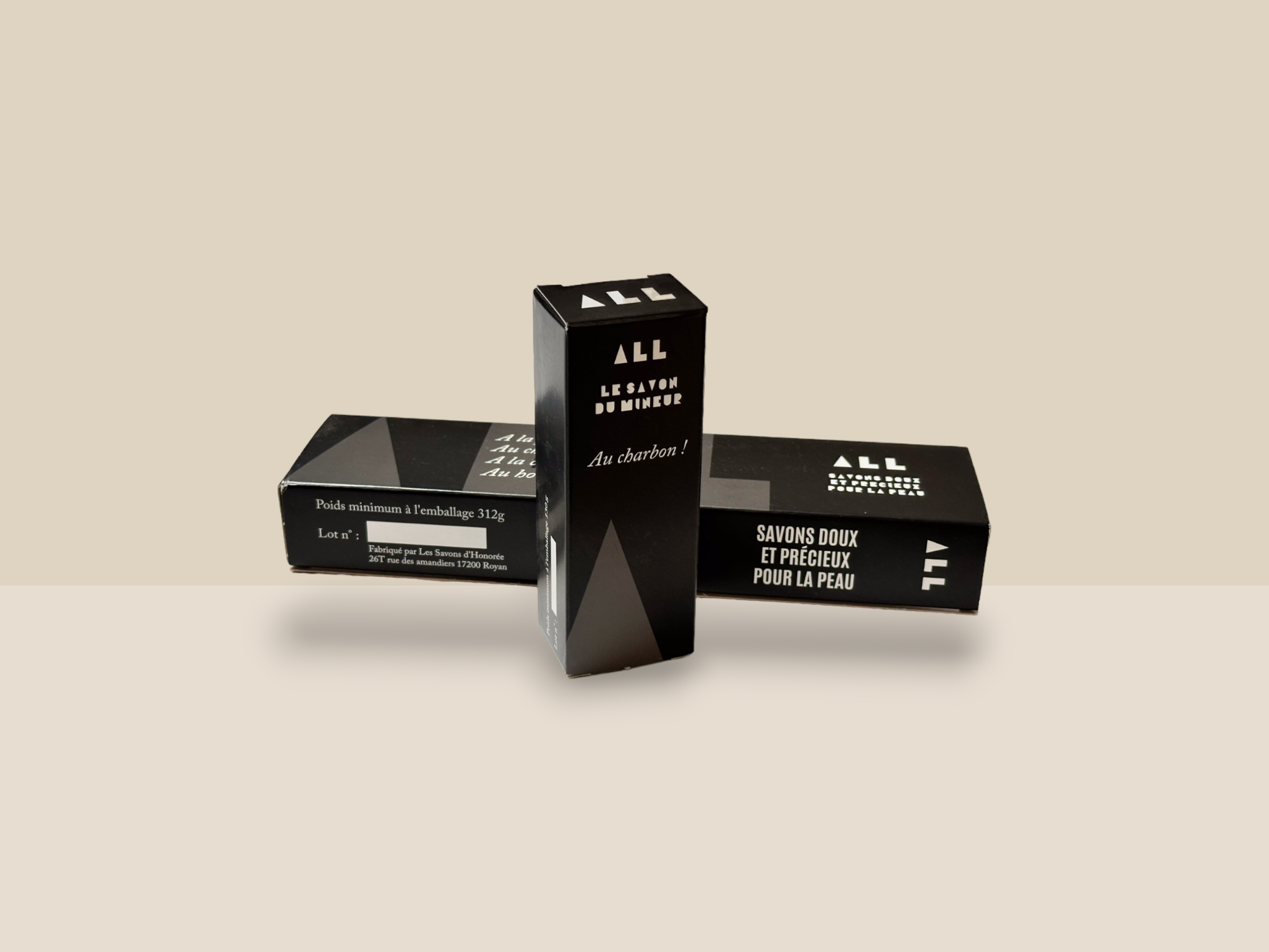 Un étui en carton allongé dans un fourreau de couleur noire et blanche avec un logo ALL. Il y a devant une petite boite noire qui porte le même logo.